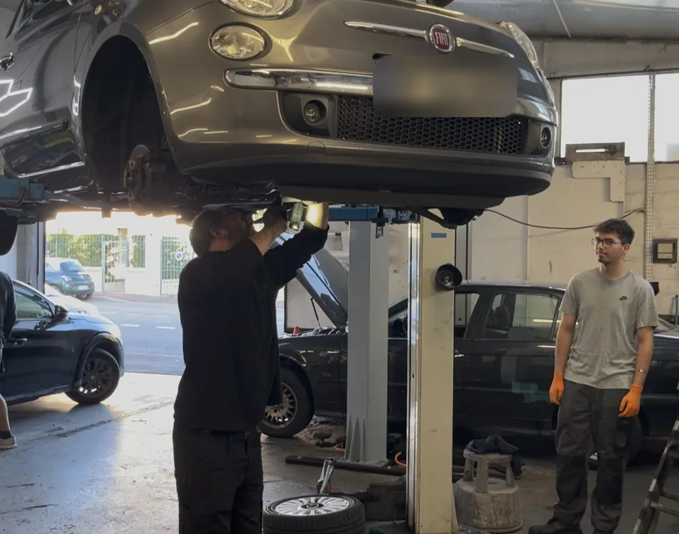 L'équipe au travail sous une Fiat 500 dans l'atelier